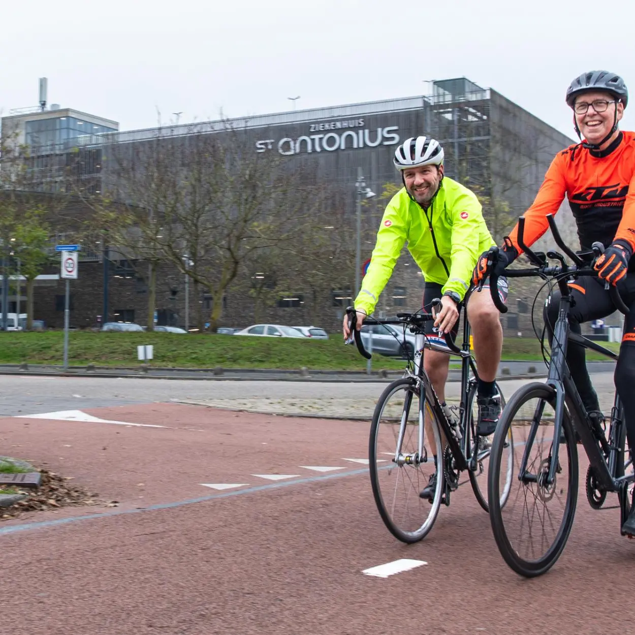 Twee wielrenners voor het gebouw van het St. Antonius 