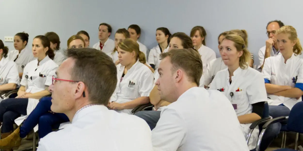 Groep dokters die bij elkaar in een zaal zitten 